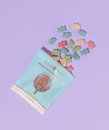 Lollipops packaging with colorful gummy bears spilling out on a purple background