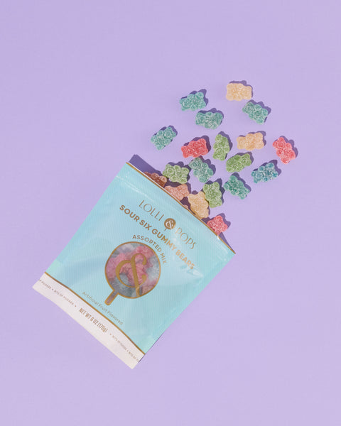 Lollipops packaging with colorful gummy bears spilling out on a purple background