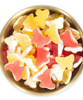 Pink and Yellow Butterfly gummy candies in a brass bowl on a white background