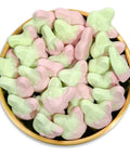 Pink and light green foxshaped swedish candy piled in a round gold bowl on a white background.
