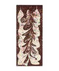 Chocolate bar with artistic design and colorful sprinkles on a pink background