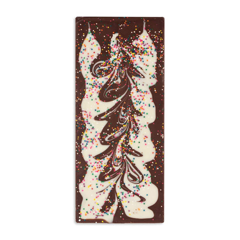 Chocolate bar with artistic design and colorful sprinkles on a pink background