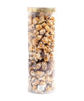 Tall cylindrical container filled with popcorn and chocolate-covered candies on a white background