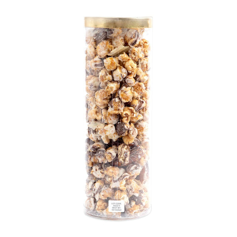 Tall cylindrical container filled with popcorn and chocolate-covered candies on a white background