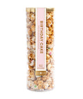 Tall cylindrical container filled with birthday cake flavored popcorn on a white background