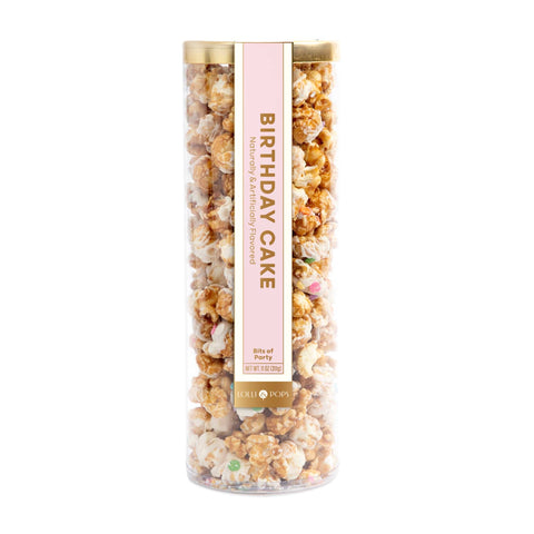 Tall cylindrical container filled with birthday cake flavored popcorn on a white background
