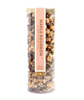Tall cylindrical container of Maple Bourbon popcorn with a pink label on a white background